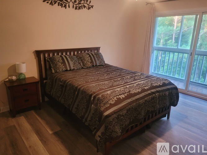 A bedroom with a large bed and a wooden nightstand.