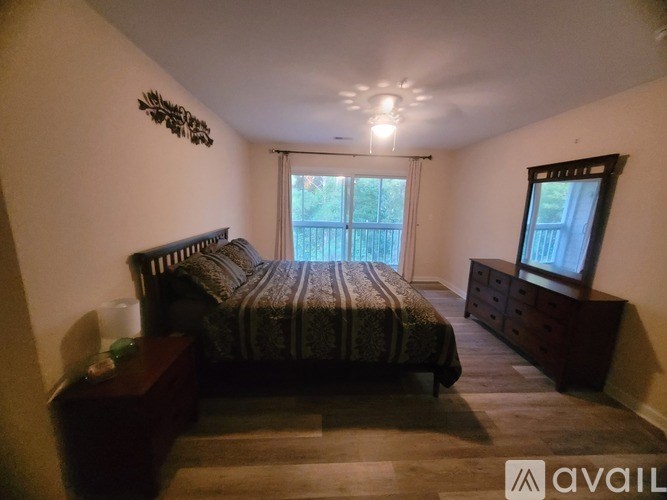 A bedroom with a bed, nightstand, and window.