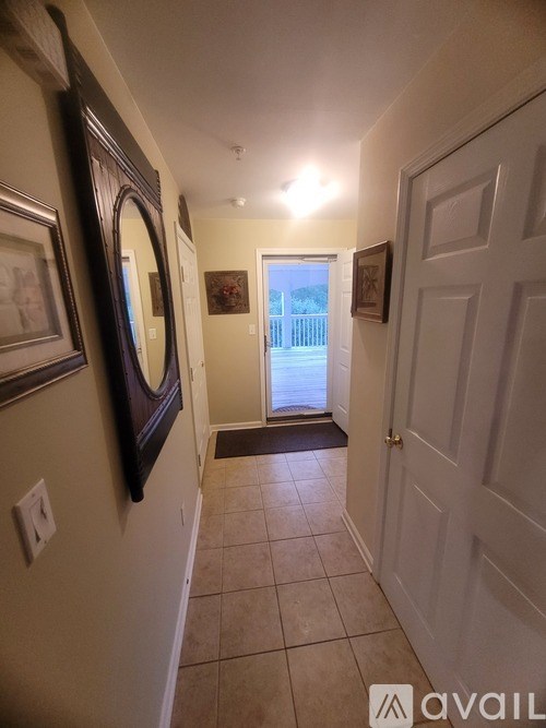 A hallway with a white door and a mirror on the wall.