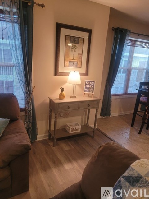 A living room with a brown couch and a small table with a lamp and a pineapple on it.