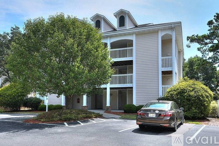 A car is parked in front of a two-story building.