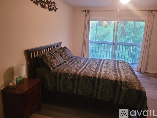 A bedroom with a large bed and a wooden nightstand.