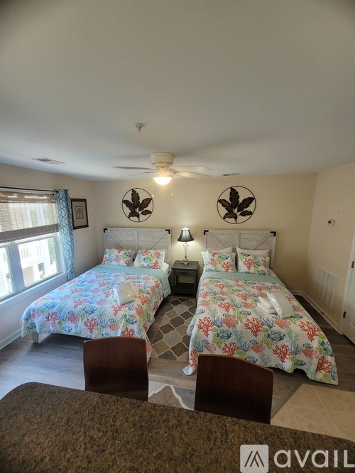 A bedroom with two beds and a ceiling fan.
