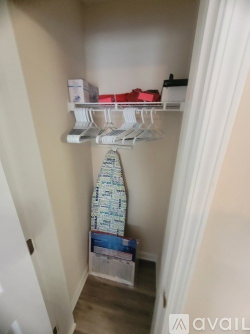 A white closet with clothes hanging and boxes on the floor.