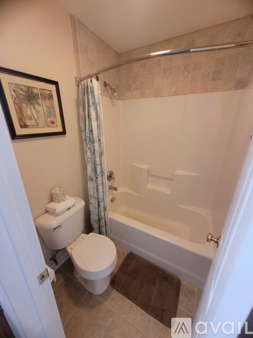 A bathroom with a toilet, bathtub, and a framed picture on the wall.