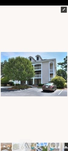 A car is parked in front of a two-story building.