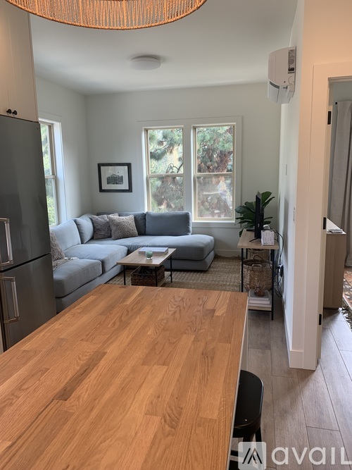 A kitchen with a wooden table and a grey couch.