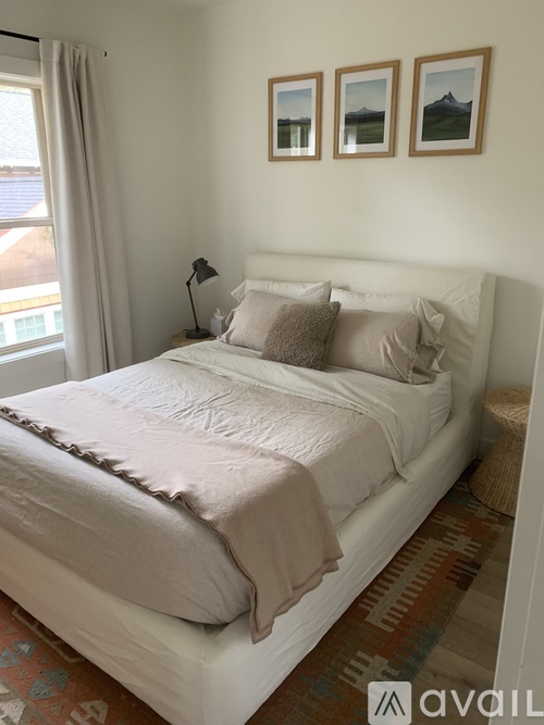 A bedroom with a large bed and three pictures on the wall.