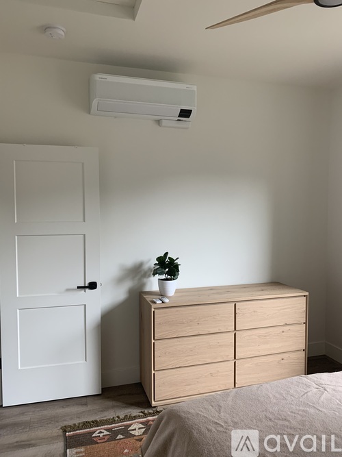 A room with a white door, a wooden dresser, and a ceiling fan.