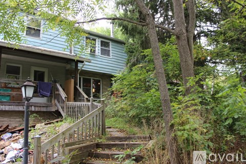 A house with a blue roof is surrounded by trees and grass.