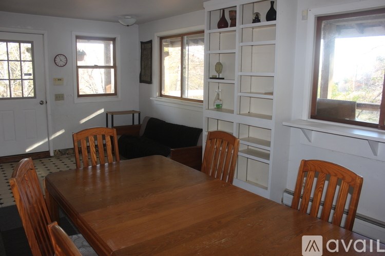A wooden dining table with chairs in a room with white walls.
