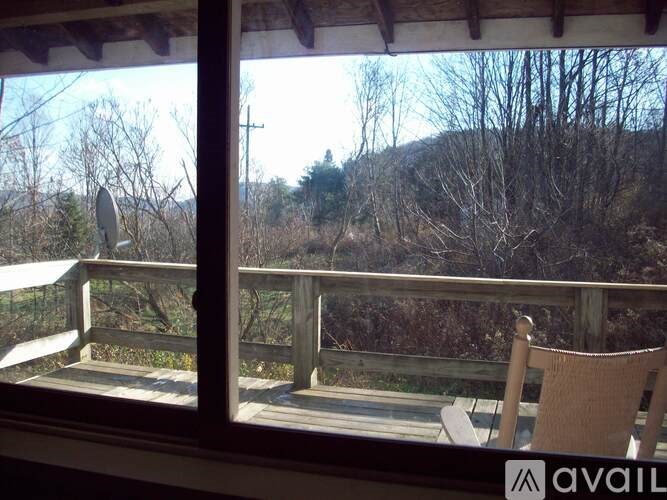 A balcony with a chair and a view of a wooded area.