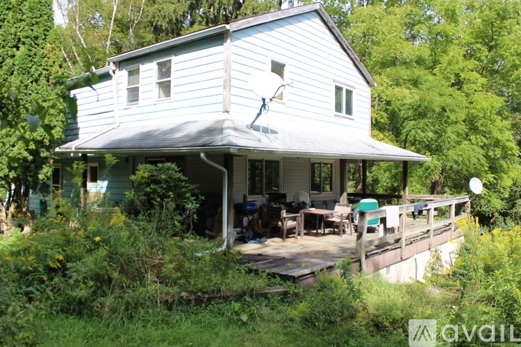 A bed with a white and blue comforter is in a room with a window.