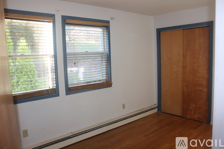 A bedroom with a bed, a table, and a window with a fan.