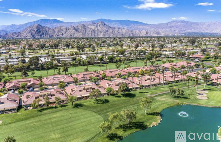 A golf course with a lake and houses in the background.