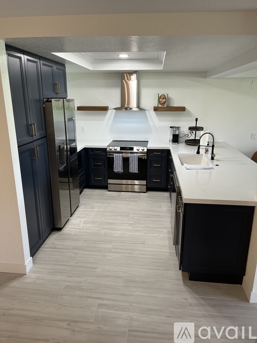 A modern kitchen with dark blue cabinets and a white countertop.