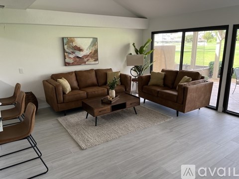 A living room with a brown couch, a chair, and a painting on the wall.