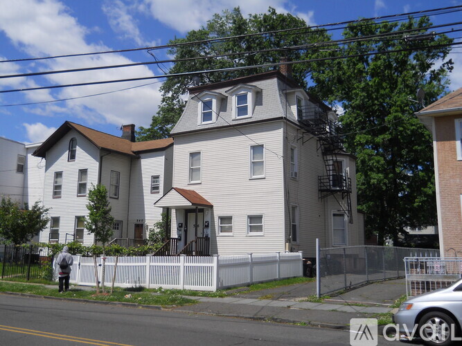 A two-story house with a white fence in front.