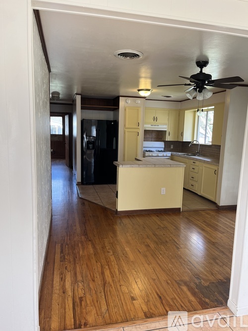 A kitchen with wooden floors and a ceiling fan.