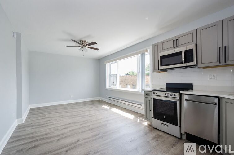 A kitchen with a fan on the ceiling and a window letting in light.