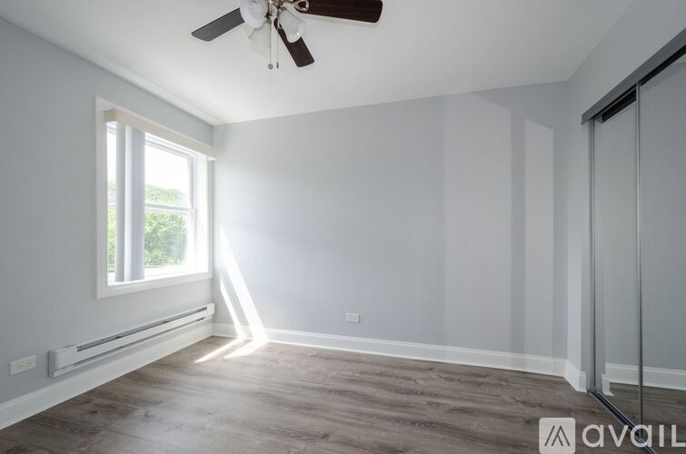 A room with a ceiling fan and a window letting in sunlight.
