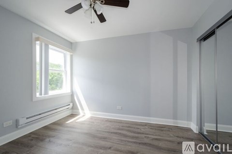 A room with a ceiling fan and a window letting in sunlight.