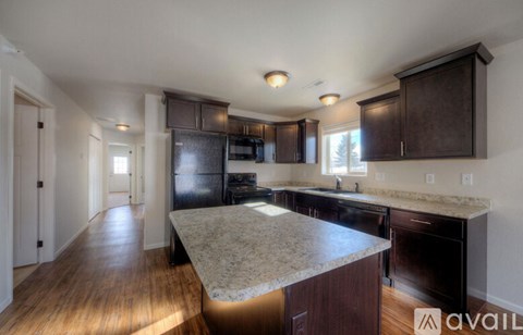 A kitchen with dark wood cabinets and a granite countertop.