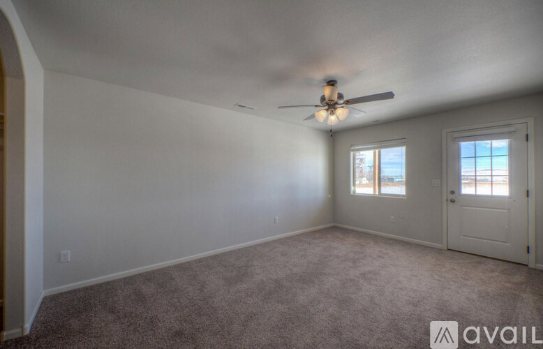 A room with a carpeted floor and a ceiling fan.