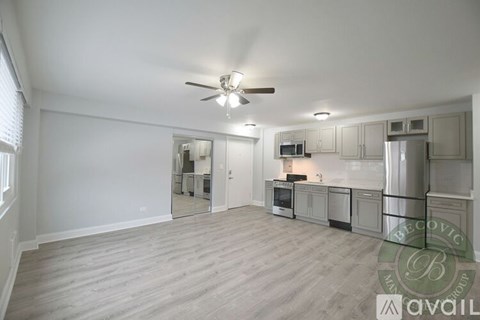 A spacious kitchen with a fan on the ceiling and a microwave on the counter.