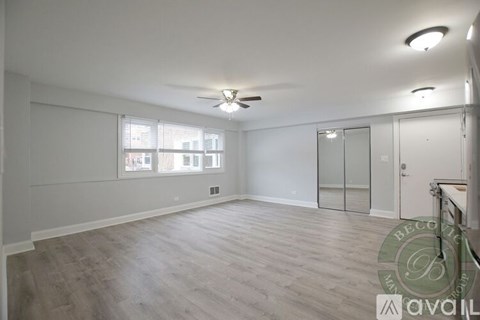 A spacious room with a ceiling fan and a window with blinds.