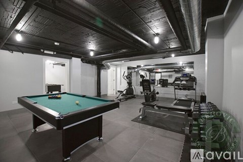 A pool table is in the middle of a room with exercise equipment.