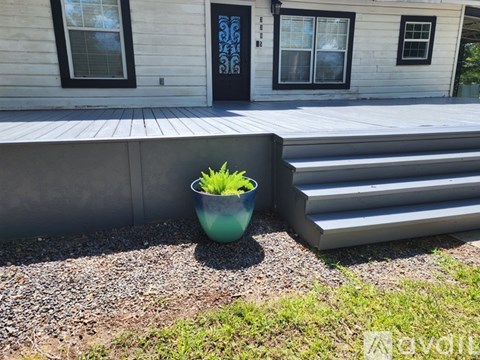 A blue bowl with green plants sits on a gravel area in front of a house.