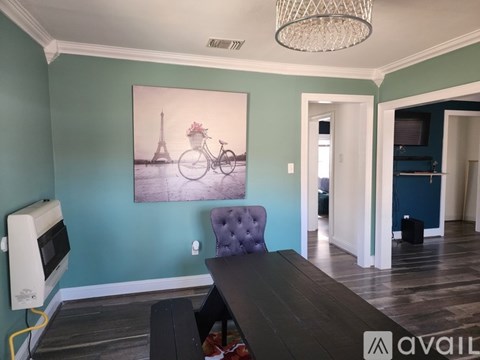 A dining room with a purple chair and a painting of the Eiffel Tower.