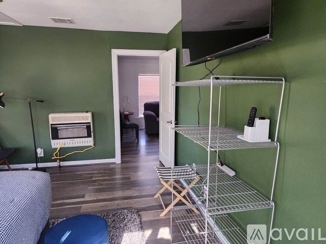 A living room with a green wall and a television mounted on it.