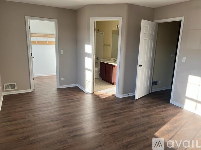 A room with wooden floors and three doors, one of which is open.