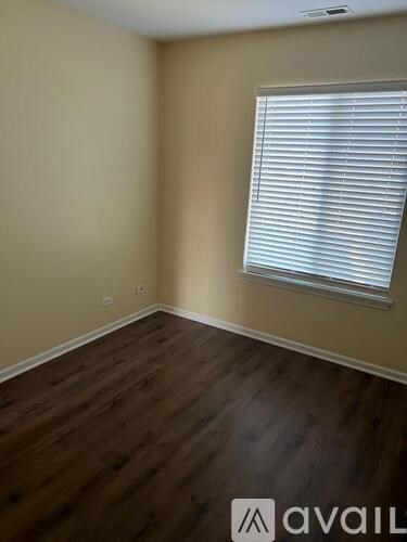 A room with wooden flooring and a window with blinds.