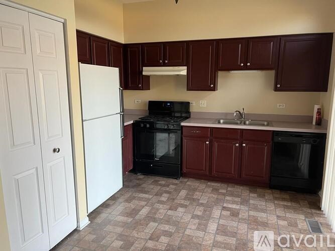 A kitchen with brown cabinets and black appliances.