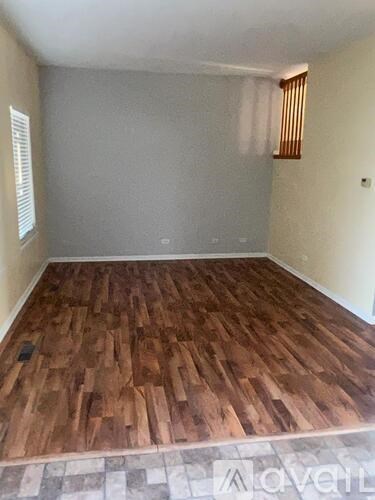 A room with wooden flooring and a window with blinds.