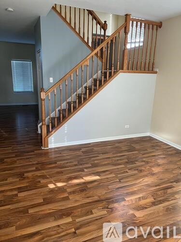 A wooden staircase with a white wall on one side and a window on the other.