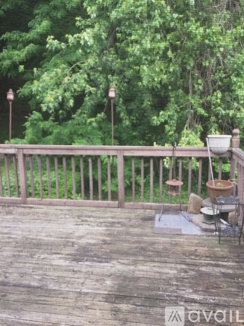 A wooden deck with a table and chairs overlooking a green forest.