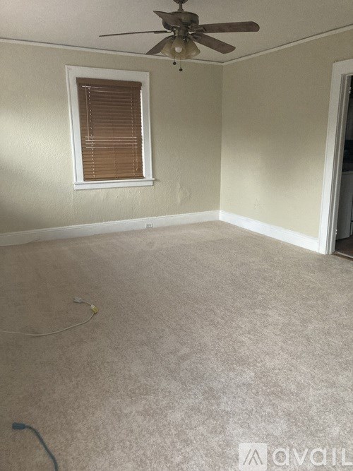 A room with a ceiling fan and a window with blinds.