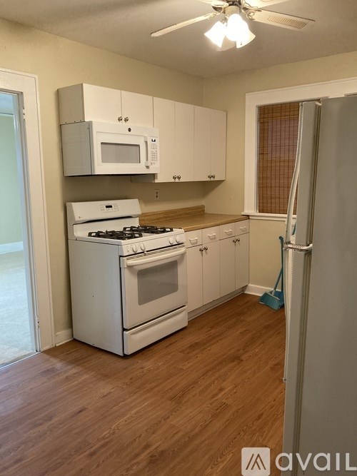 A kitchen with white appliances and wooden floors.