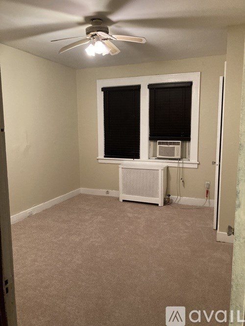 A room with a ceiling fan and a window with blinds.