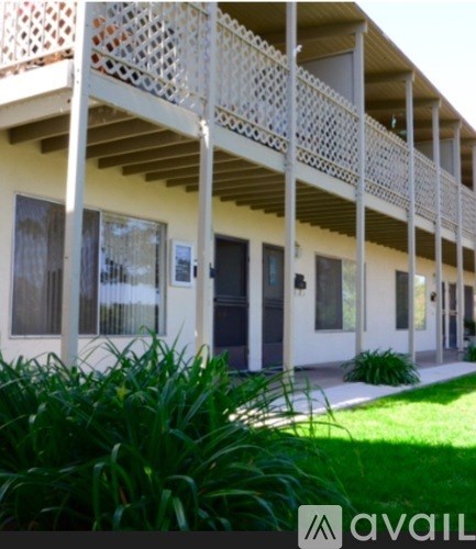 A white building with a balcony and a green plant in front.