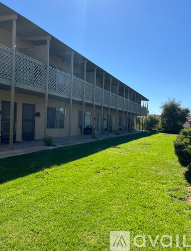 A building with a balcony and a green lawn in front.