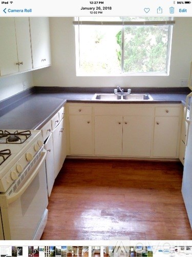 A kitchen with white cabinets and a black countertop.