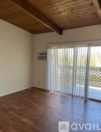 A room with wooden floors and a window with blinds.