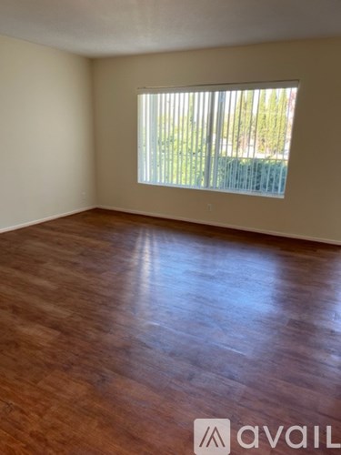 A room with wooden flooring and a window with blinds.