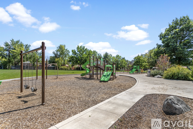 A playground with swings and slides surrounded by trees.
