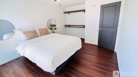 A bedroom with a white bed and a round mirror on the wall.